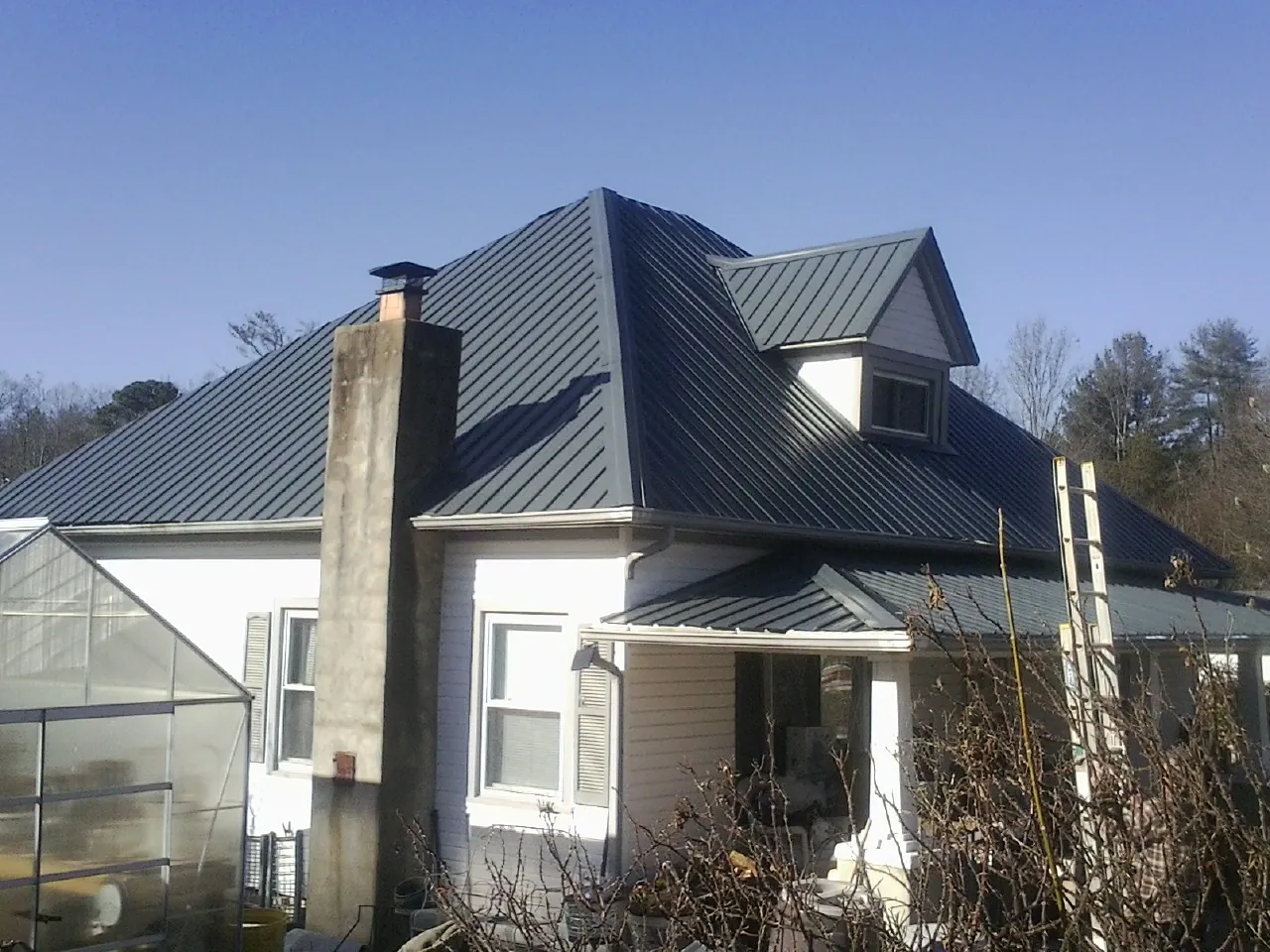 Dark blue standing seam metal roof on a white farmhouse with dormer — Slate & Tile Roof Repair by Roofing Brothers in Urbana