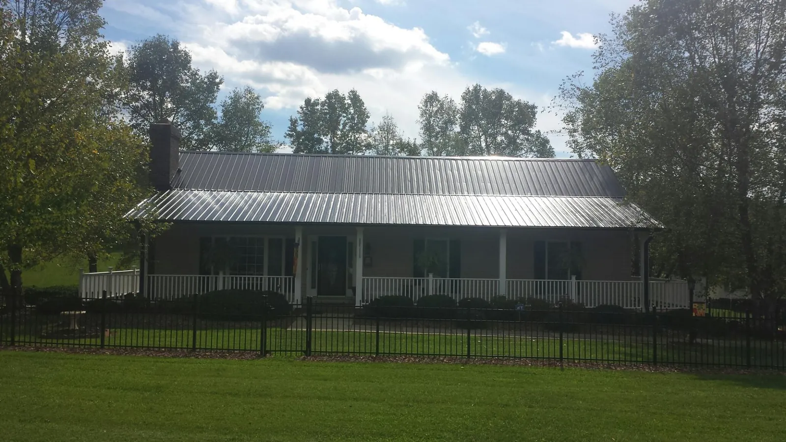 Gray metal roof on a brick ranch with a full width front porch — Gutter Guard Installation work by our crew in Urbana