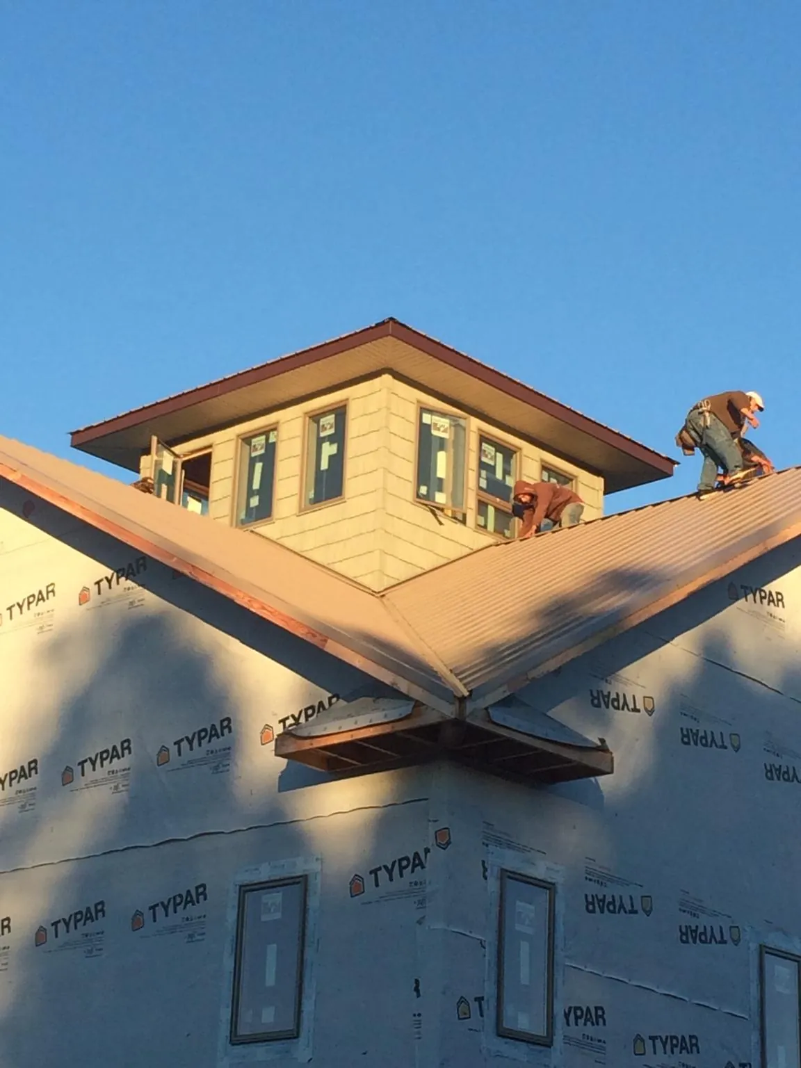 Roofers working around a rooftop cupola on a new metal roof at sunset — Roof Waterproofing in Urbana by Roofing Brothers